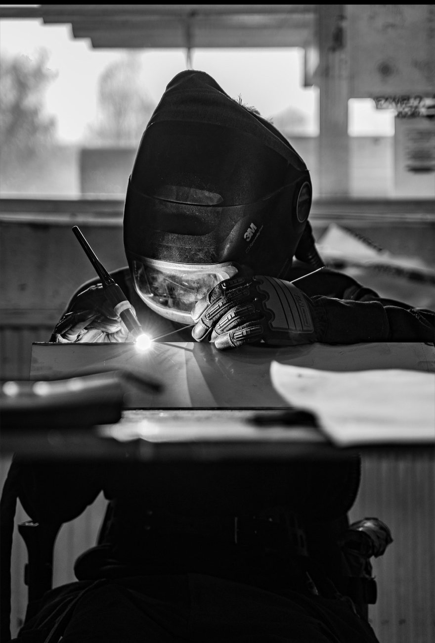 Welder TIG welding with hood down, arc lit